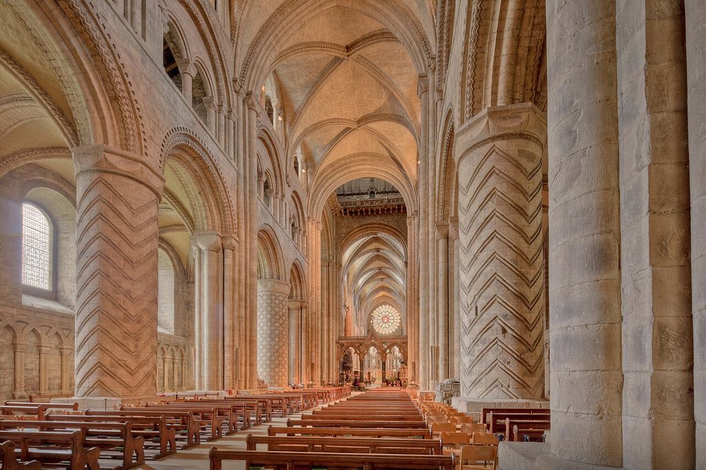 Heavy patterned supports carry round arcades below a ribbed stone vault.