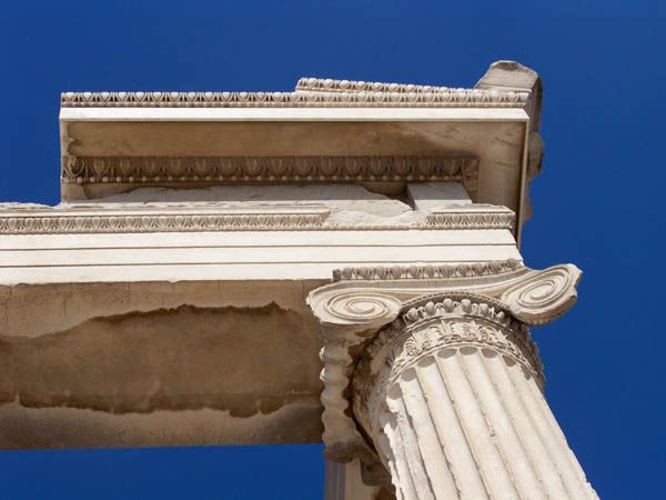 Paired scrolls spread above a fluted shaft beneath layered carved horizontal bands.