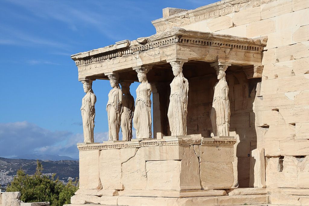 Draped female figures with capitals on their heads stand beneath the porch entablature.
