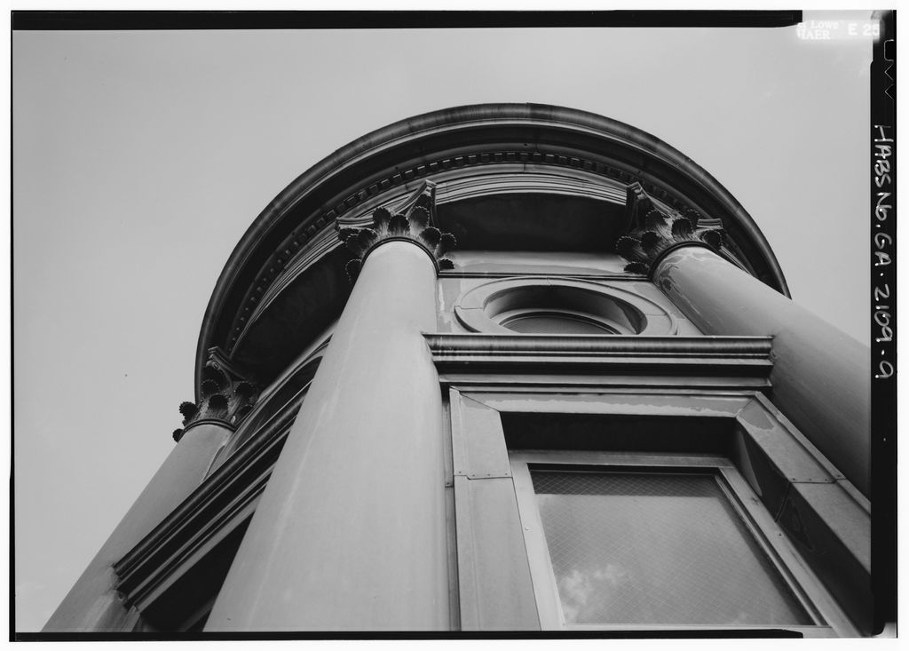 A monochrome low-angle detail shows a round columned and glazed cupola stage beneath a small metal dome.