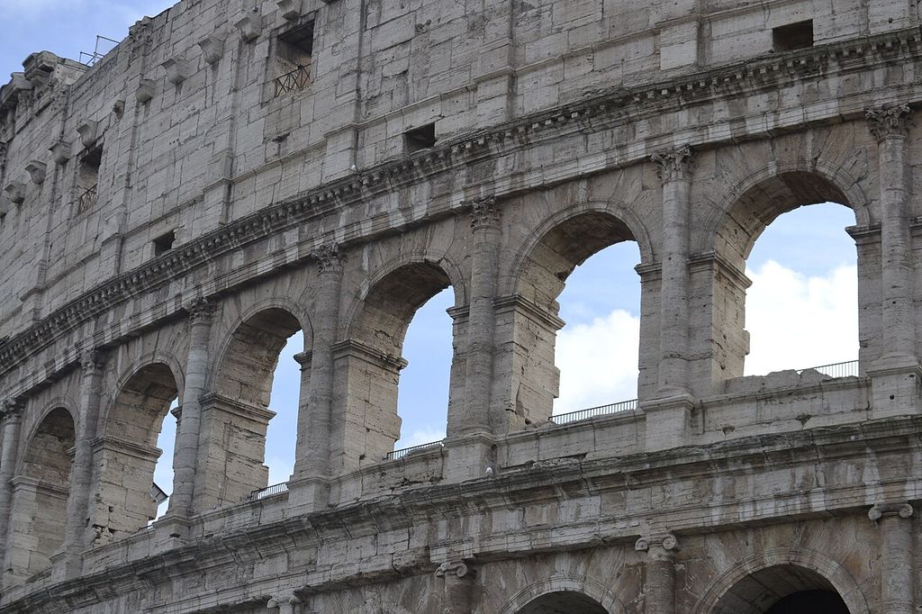 Repeated stone arches are divided by engaged columns and crossed by long horizontal moulded bands beneath the attic wall.