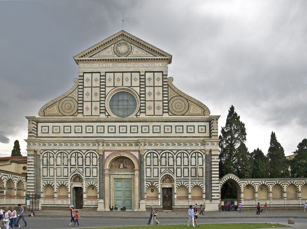 A symmetrical green-and-white marble church front surrounds a large circular window above three portals and a public square.