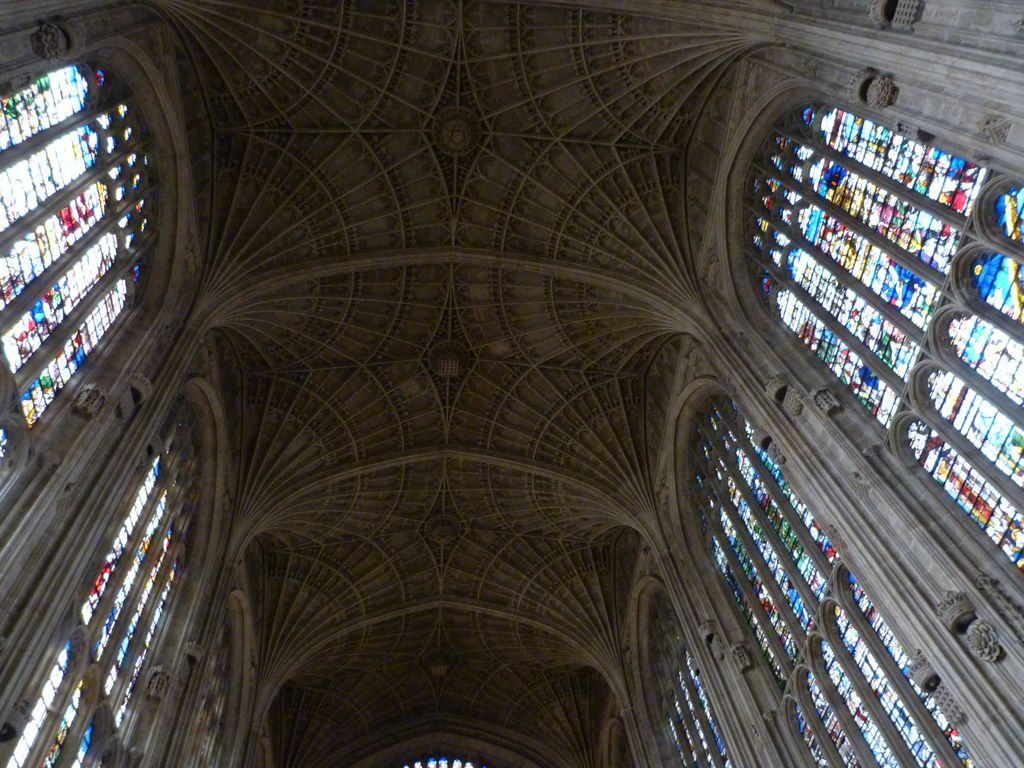 Broad rows of stone fan vaults and central patterned fields extend above tall stained-glass windows in King's College Chapel.