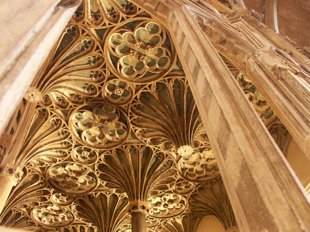 Compact fan ribs rise between slender supports amid painted cusped panels and circular flower-like bosses.