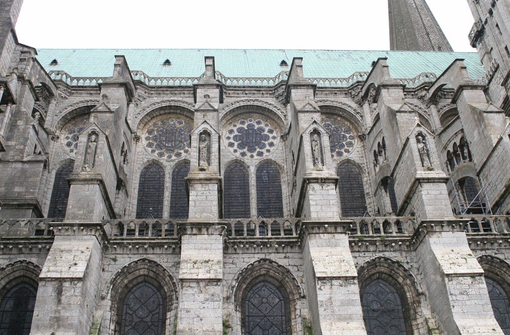 Stone buttresses rising beside the north nave windows of Chartres Cathedral, with arched braces visible at the sides.
