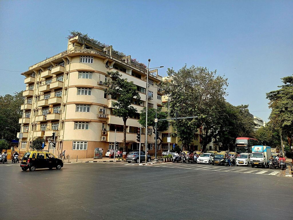 Pale apartment building with rounded corner balconies overlooking a busy street near Mumbai’s Oval Maidan.