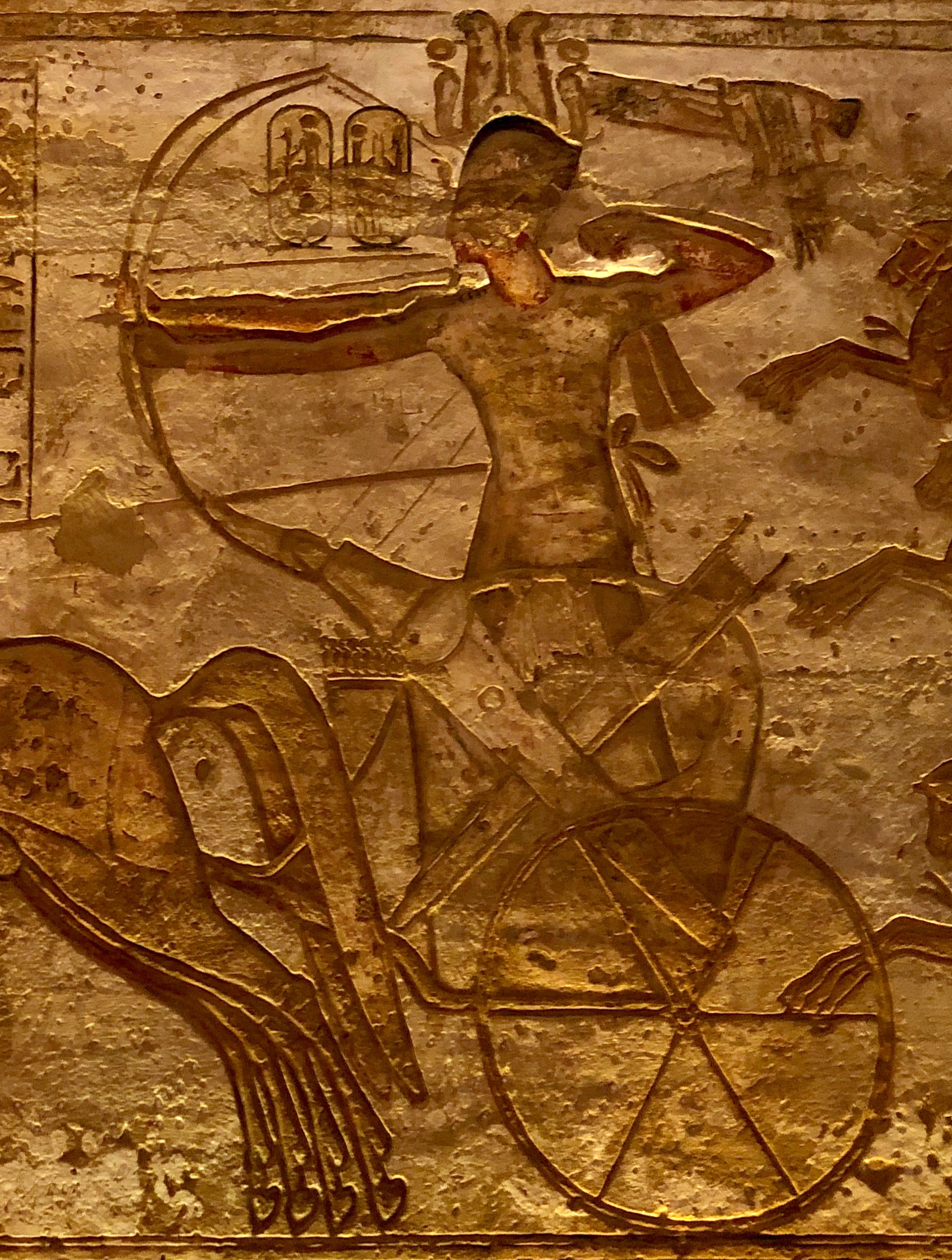 Sandstone relief of Ramesses II drawing his bow from a chariot on the Great Temple Qadesh wall.