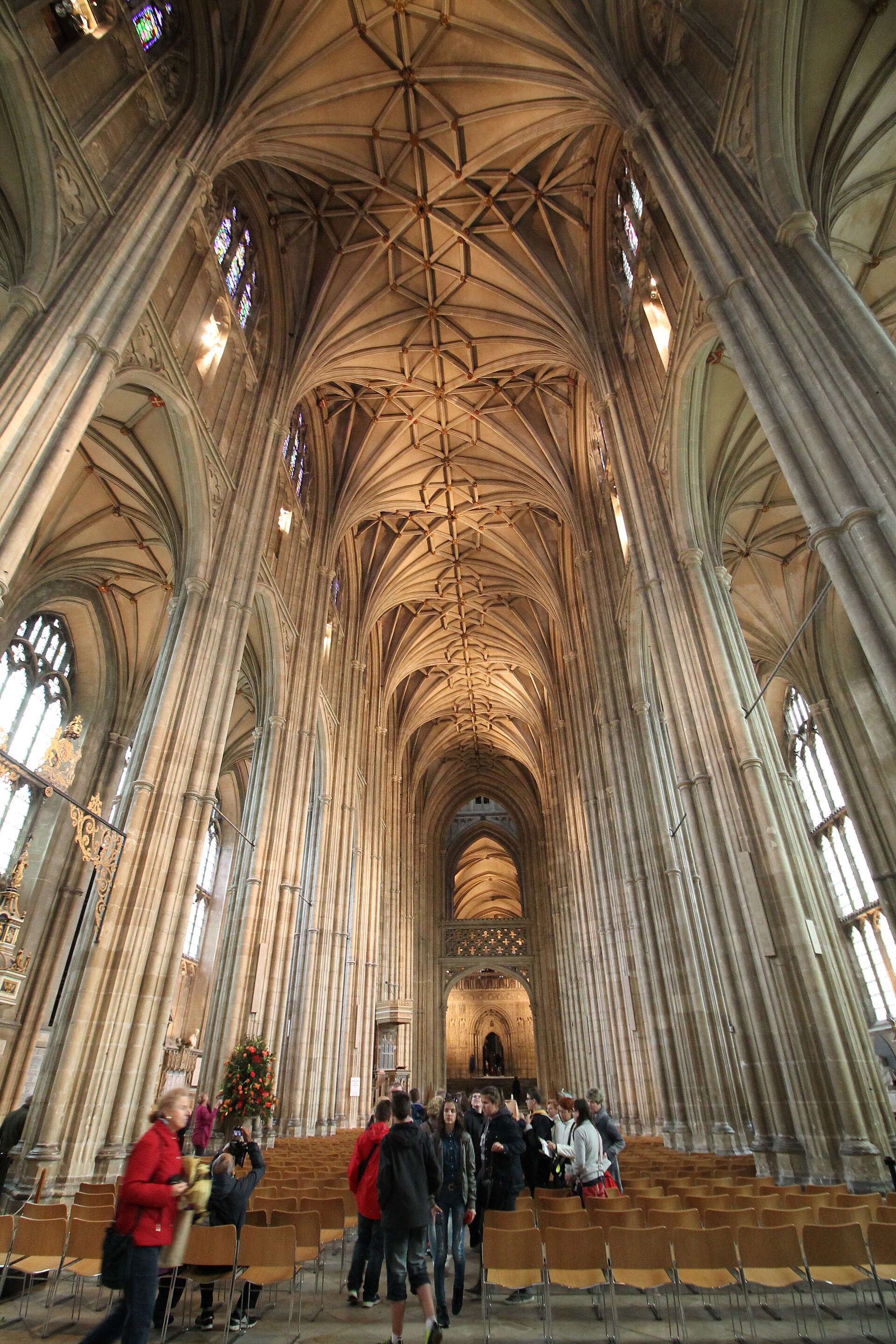 Canterbury Cathedral's long Perpendicular nave looking east beneath a dense lierne vault toward the solid pulpitum crossing screen.