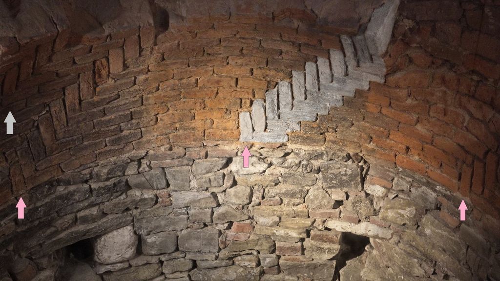 Curved courses of old brick surround recurring upright bricks in a museum dome model, with several pink and white arrows added to the source image.