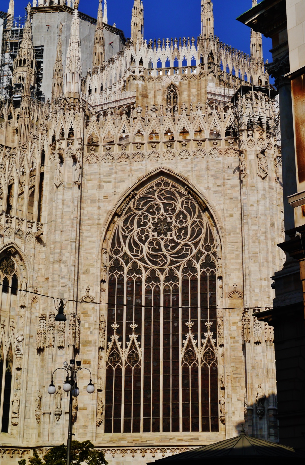 The cathedral’s tall central apse window seen from outside, its dense curvilinear tracery rising beneath galleries, pinnacles and the tiburium.