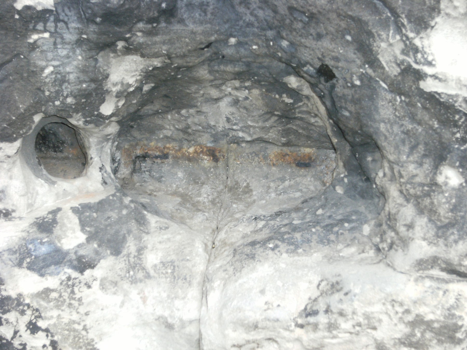 Close view of darkened Porta Nigra stonework with a central joint, recesses and uneven retained surfaces.
