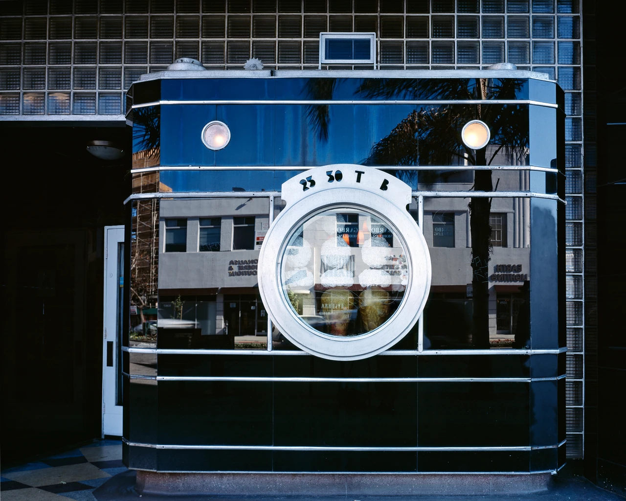 The Darkroom storefront has dark reflective glass, silver-coloured horizontal trim and a large circular window resembling a camera lens.