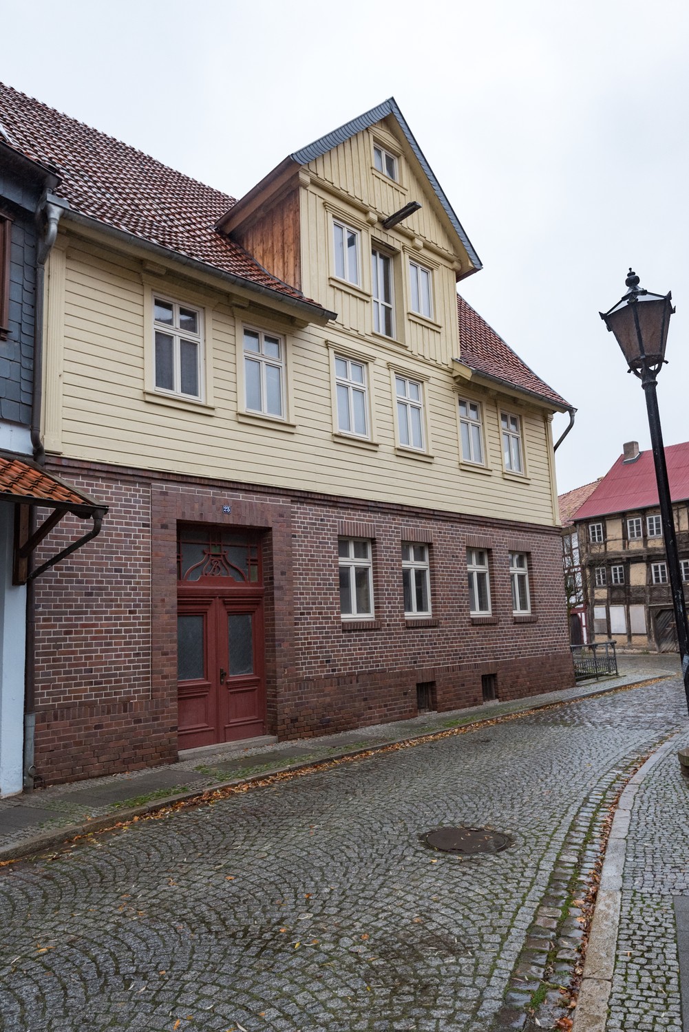 Street front of Hagen 25 in Osterwieck, with a brick ground floor, pale boarded upper wall and gable, and a red-tiled roof.
