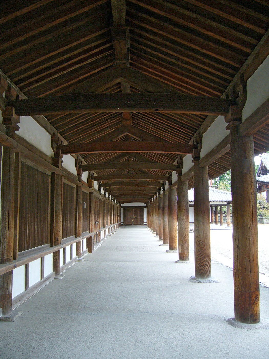 Timber veranda at Horyu-ji with rows of posts, bracketed beams, boarded walls and deep roof shelter.