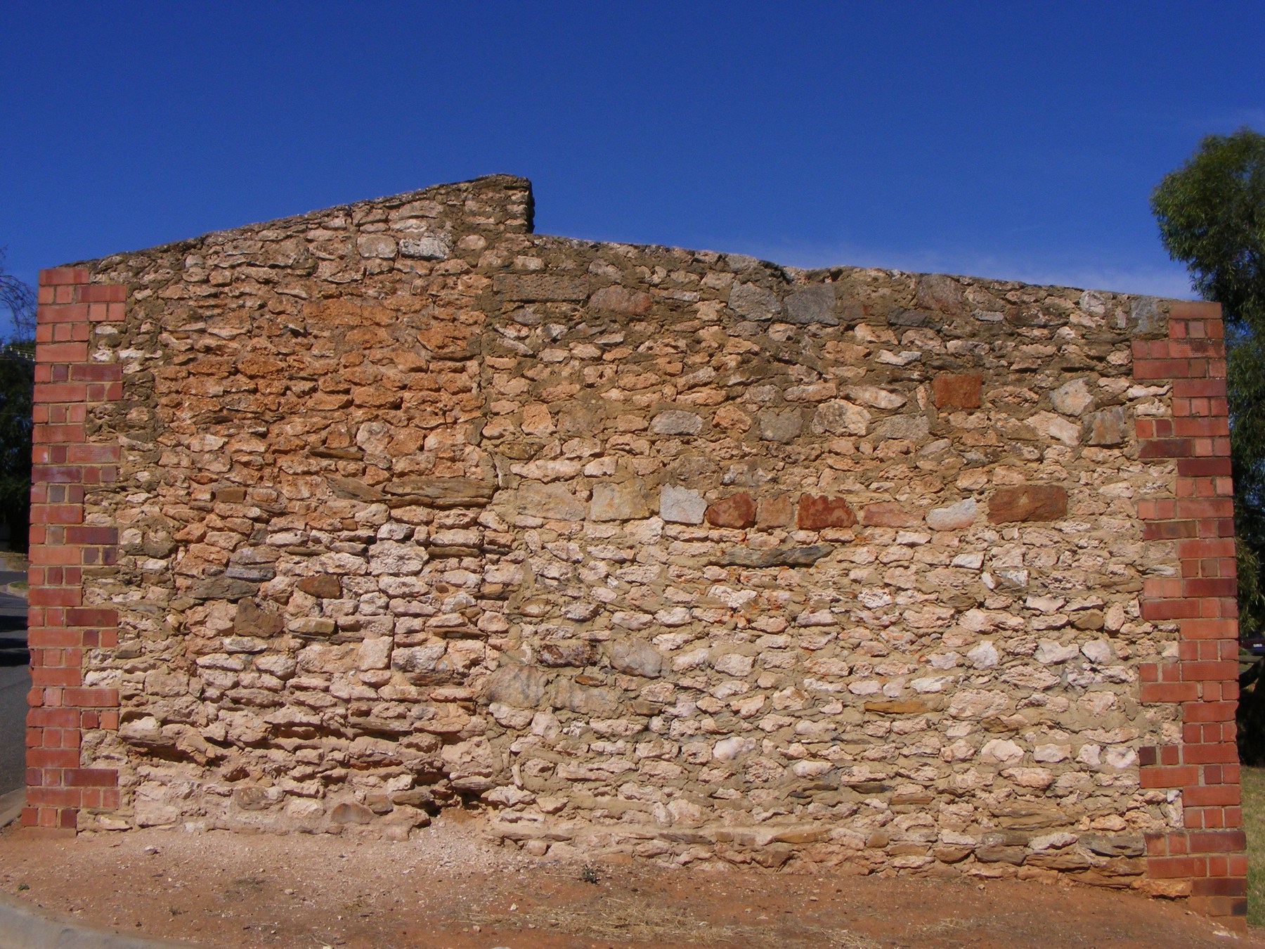 Irregular stone wall framed by red brick corners.