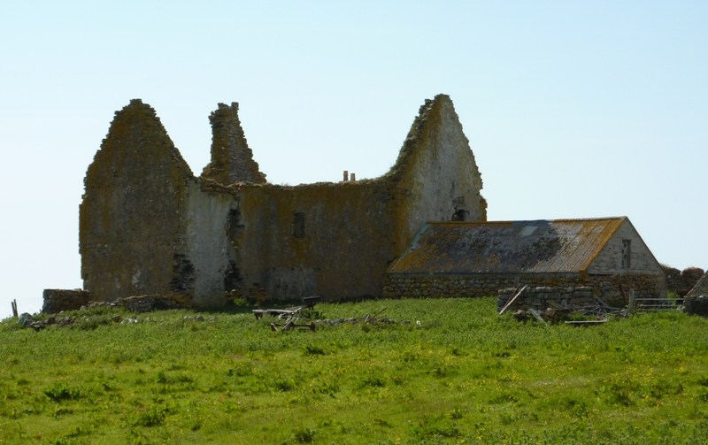 Roofless high stone gables at Ormacleit with broad pale coating patches and a low roofed building alongside.