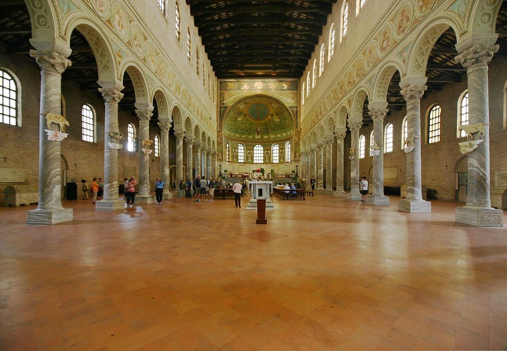 Two long arcades and a timber roof frame a distant curved sanctuary with windows and a mosaic semi-dome, with visitors and furnishings below.