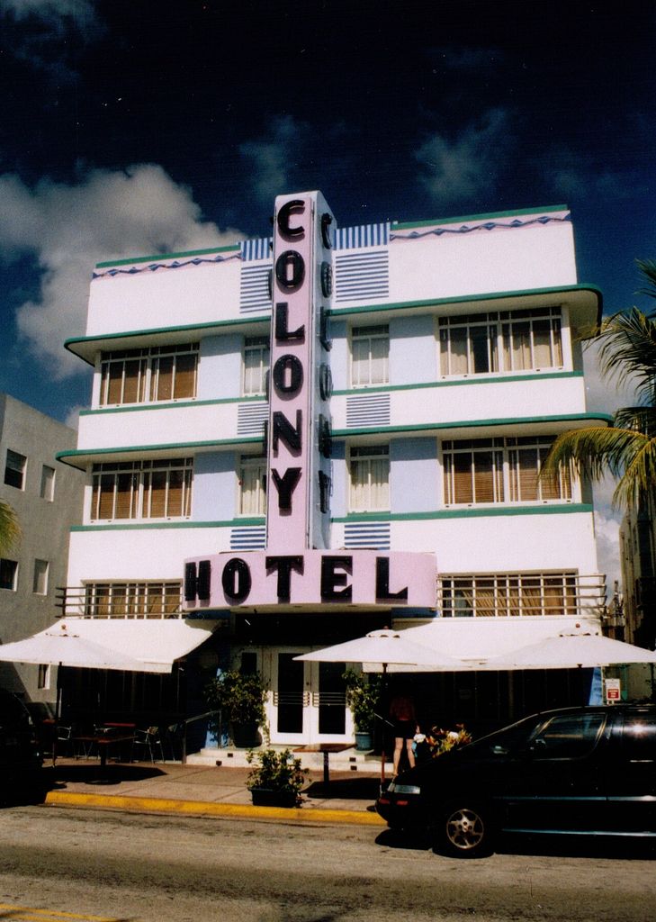 A low-rise hotel combines a central vertical sign with horizontal windows and projecting sunshades.