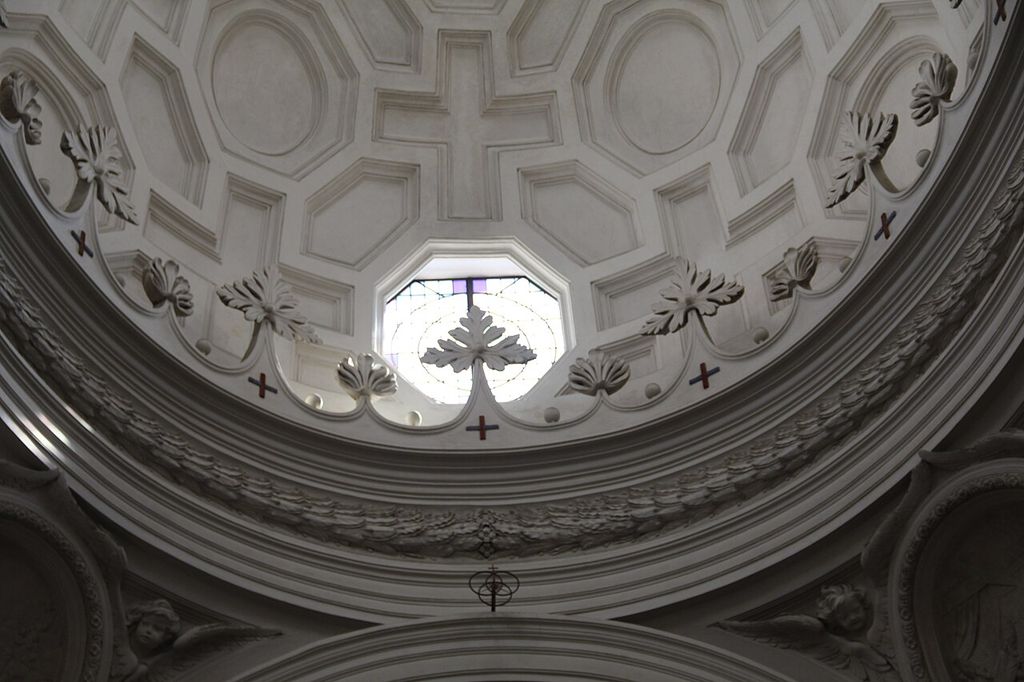 Geometric coffers above a curved cornice and window inside San Carlo alle Quattro Fontane.