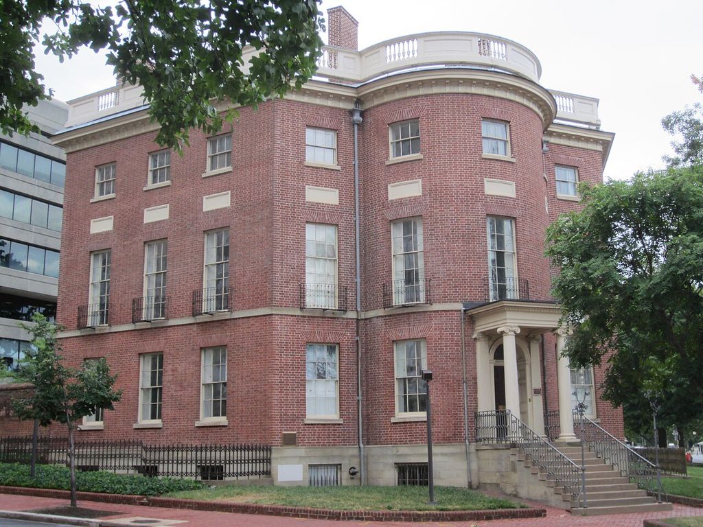 A rounded brick entrance bay projects from a multi-storey house with tall sash windows.