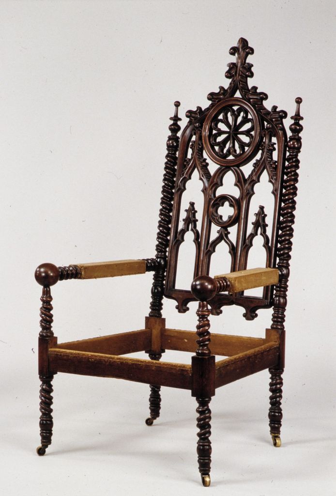 A wooden chair frame has a tall pointed tracery back with a rose-window motif, spiral posts and legs, and an open seat frame.