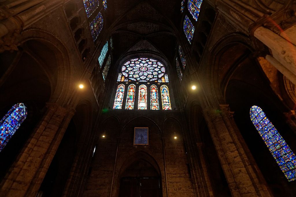 Bright coloured rose and lancet windows framed by the dark stone walls and arches of Chartres’s north transept.