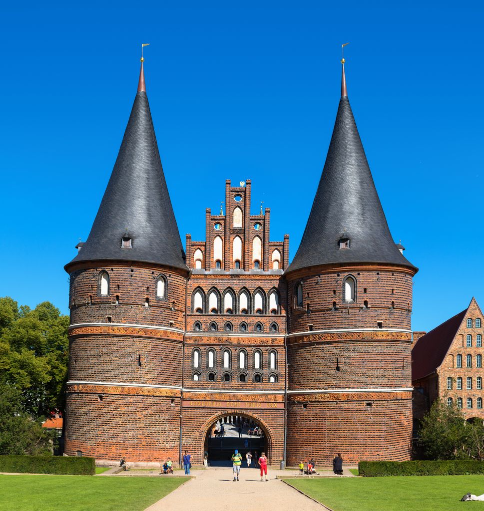 Twin round brick towers with conical roofs flank a stepped gable and gateway at Lübeck’s Holstentor.