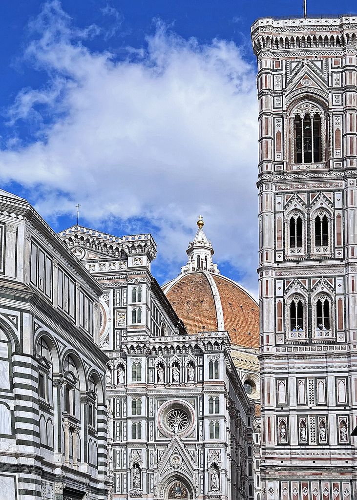 Terracotta dome and lantern behind Florence Cathedral’s patterned exterior, beside the tall bell tower.