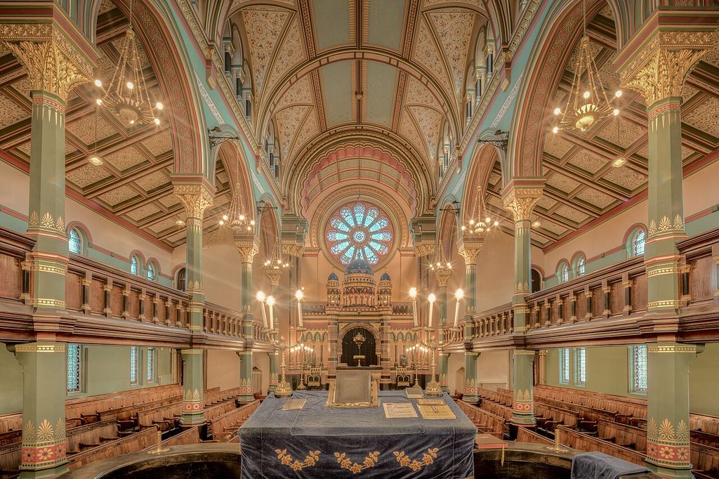 Decorated columns support galleries and a patterned ceiling around a long interior with a rose window at the far end.