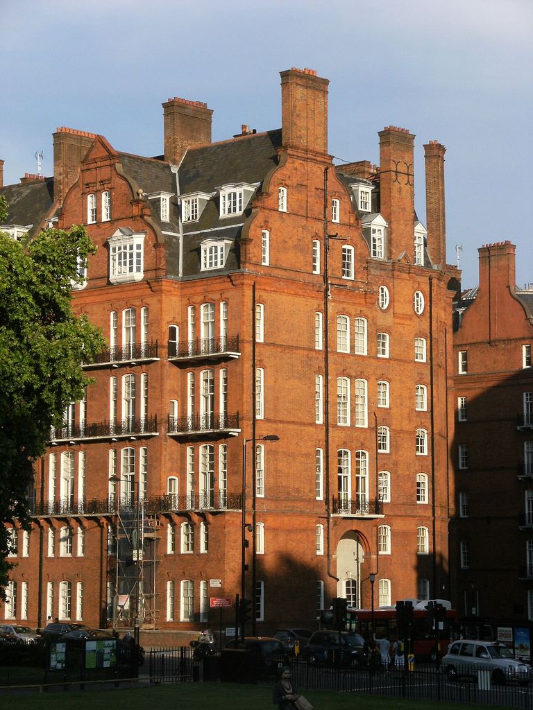 A tall red-brick apartment block with shaped gables, large chimneys and white sash windows.