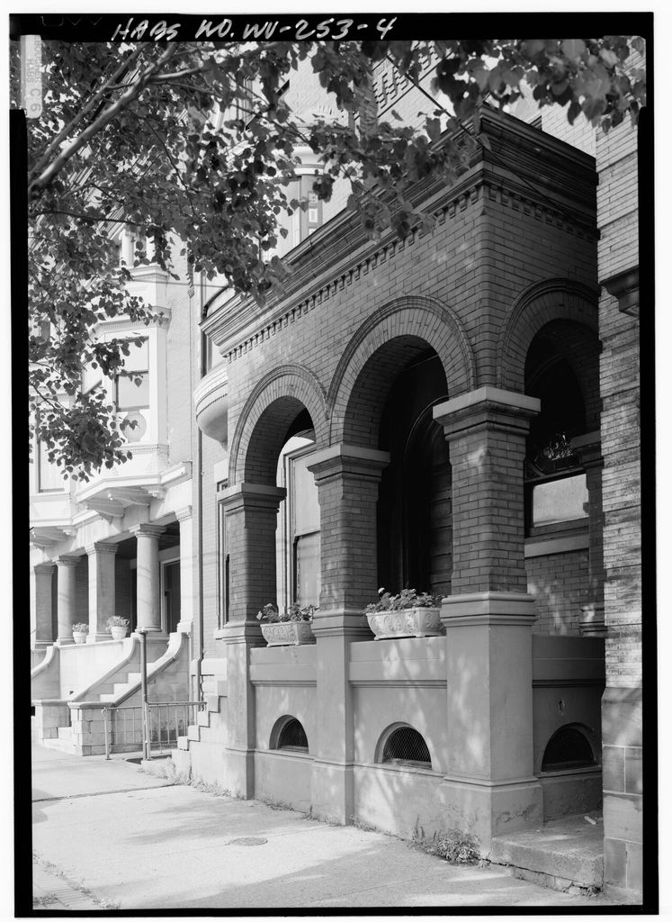 Black-and-white survey photograph of a round-arched brick porch with heavy piers and steps.