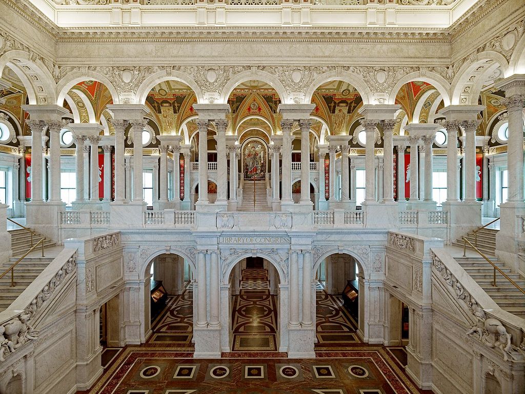 Broad stairs and two levels of decorated arcades surround a large marble hall.