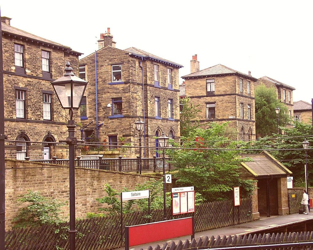 Stone houses with repeated sash windows and chimneys overlook the railway platform at Saltaire.