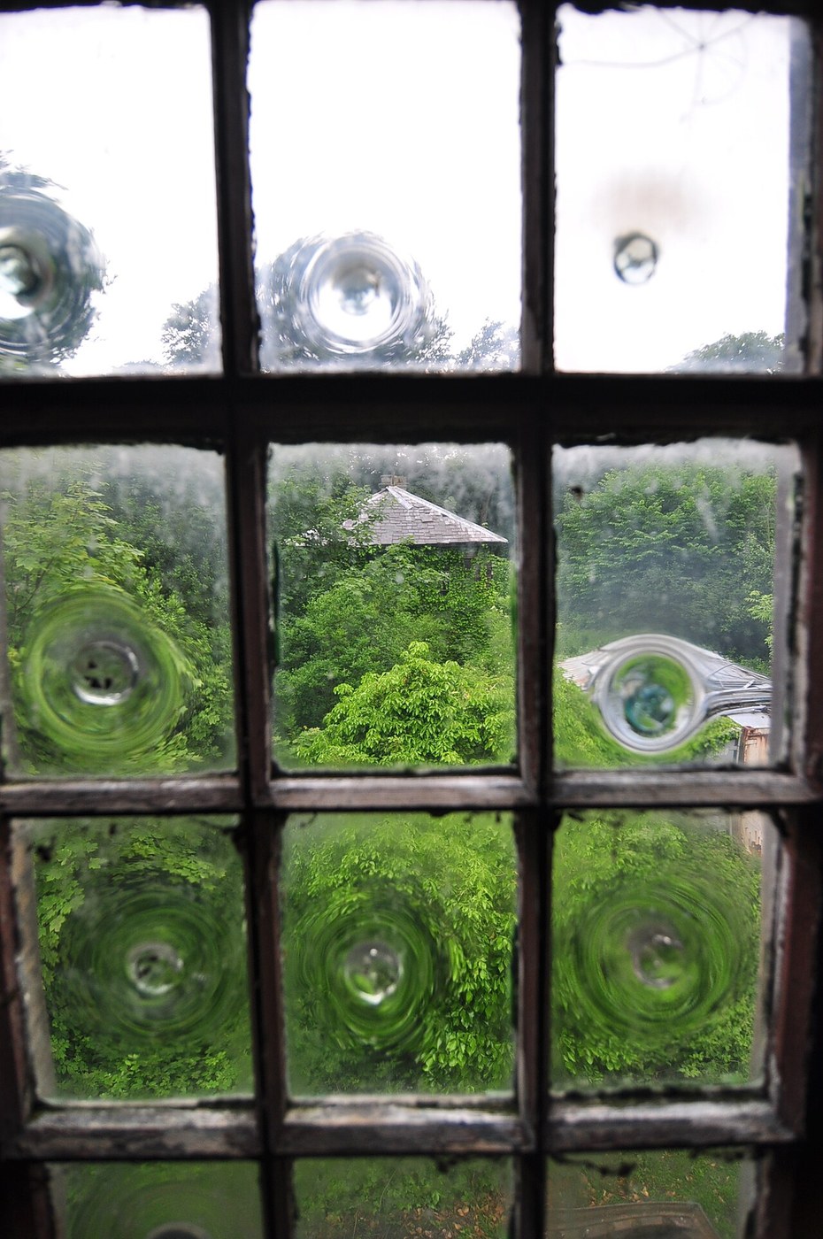 Close view of a circular bull’s-eye in a rippled crown-glass pane held within a rectangular frame.