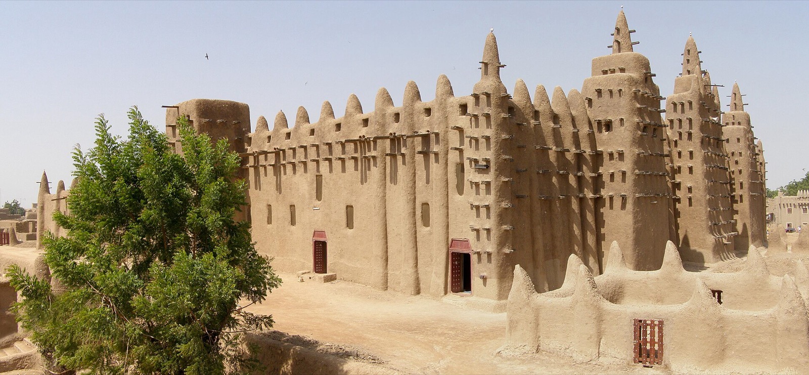 Earthen Great Mosque of Djenné and adjacent low town walls with towers, buttresses and projecting timbers.