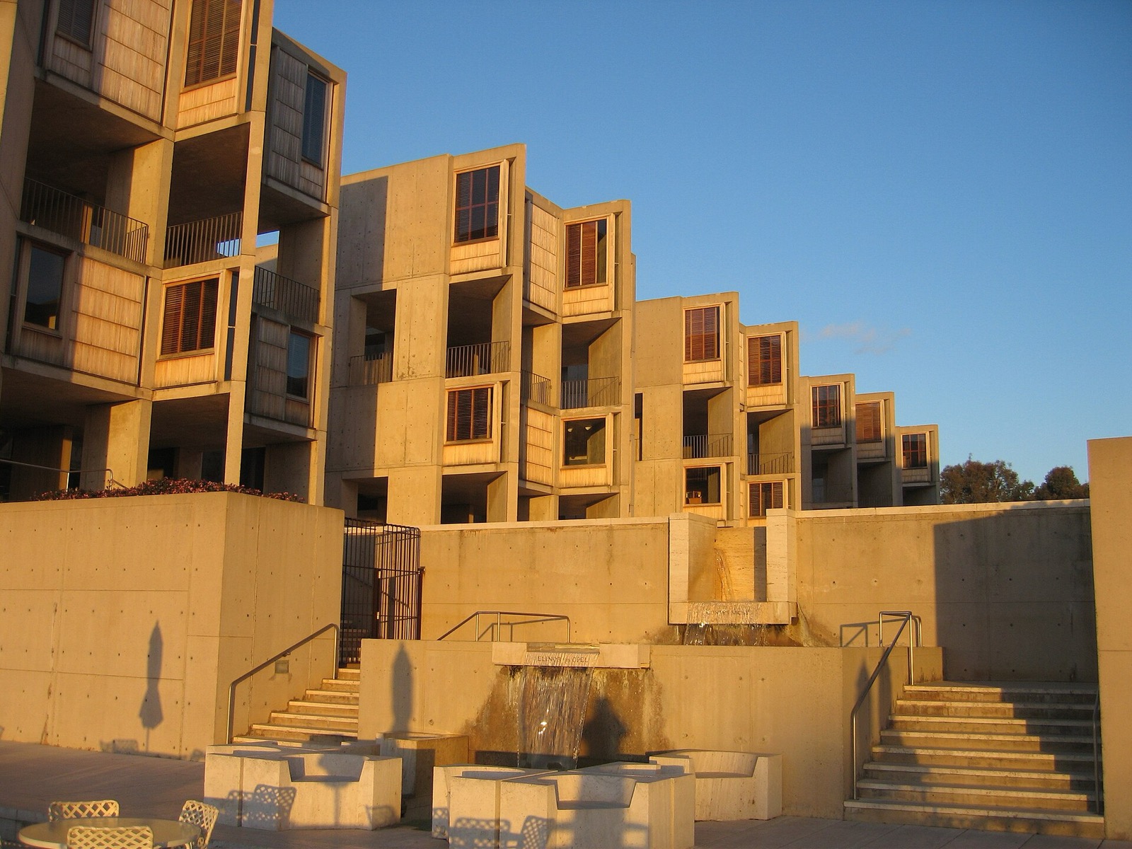 Salk Institute study towers receding beside courtyard and stepped water feature in evening light.