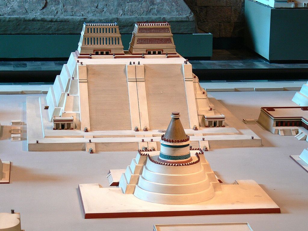 A museum model shows a large twin-stair temple platform with two summit shrines behind a smaller round temple and low precinct buildings.