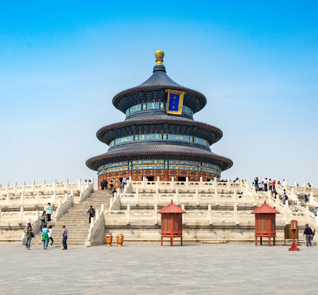 A circular blue-tiled hall with three broad eaves rises above white marble terraces filled with visitors.