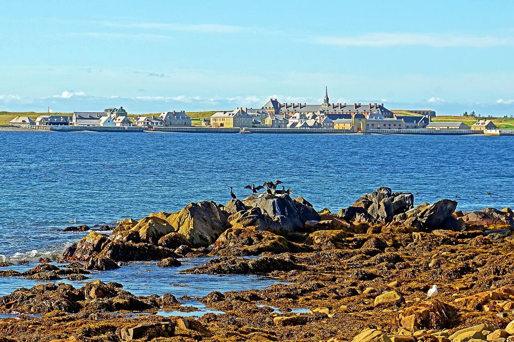 Low waterfront ranges and larger buildings stand above a harbour shoreline under a broad sky.
