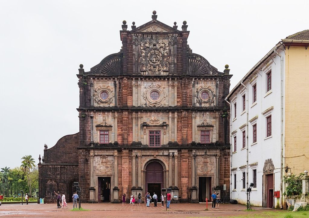 An elaborate stone church front has stacked columns, several levels of openings, carved reliefs and curved upper shoulders.