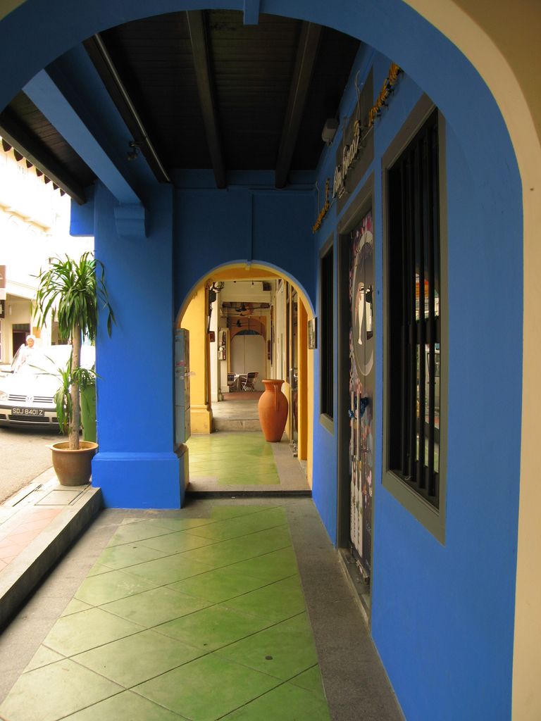 A covered walkway passes through successive arches beside shopfronts, with openings to the street.