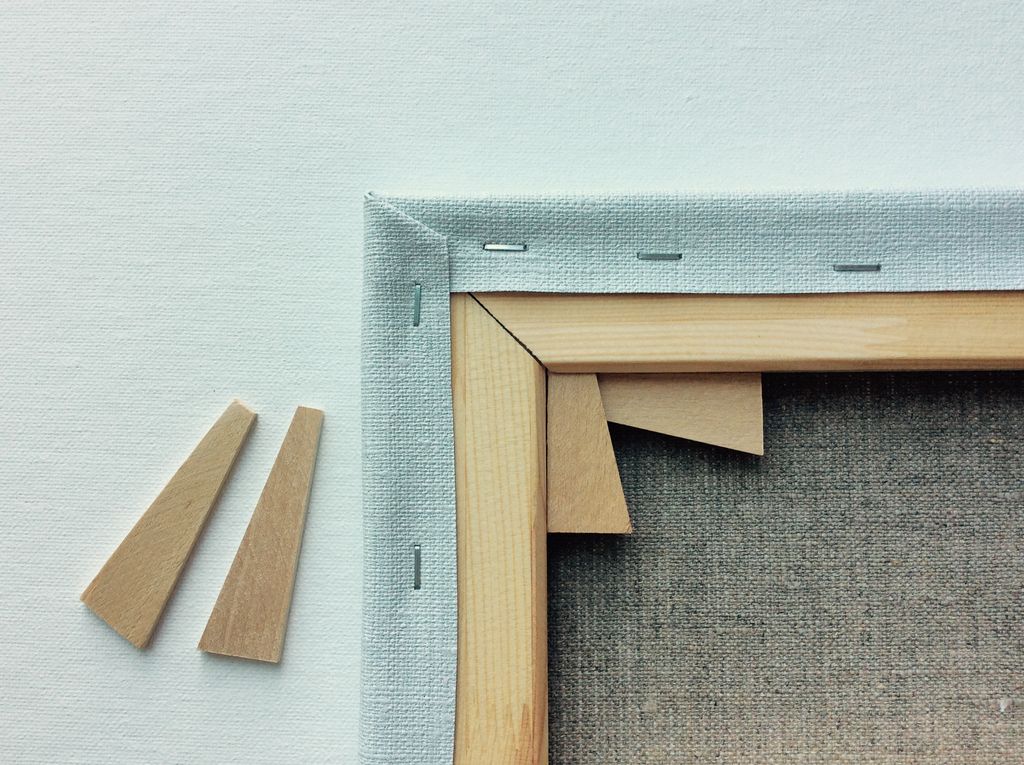 Close rear view of canvas weave, staples, a wooden stretcher corner and loose keys.