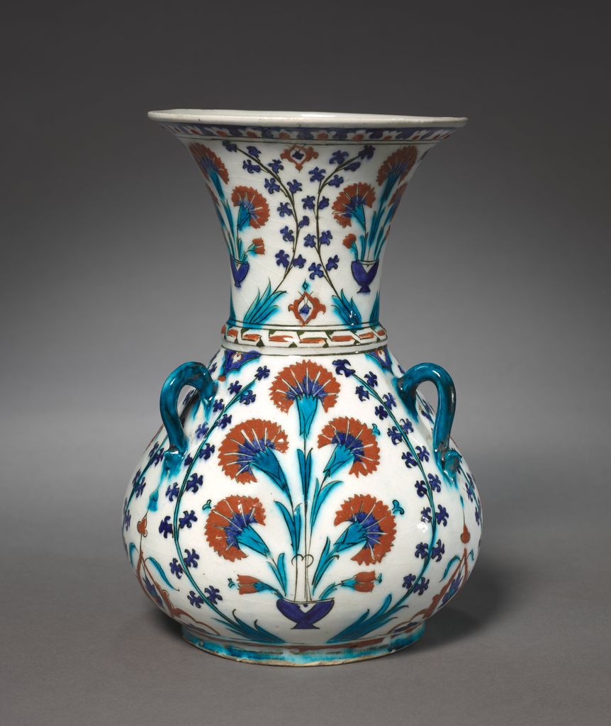 An Ottoman ceramic mosque lamp has a narrow neck, rounded body, projecting handles and a small foot covered with blue decoration.
